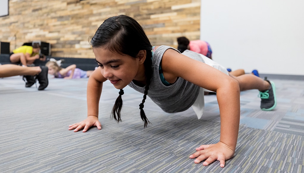 Little girl doing pushups in gym class