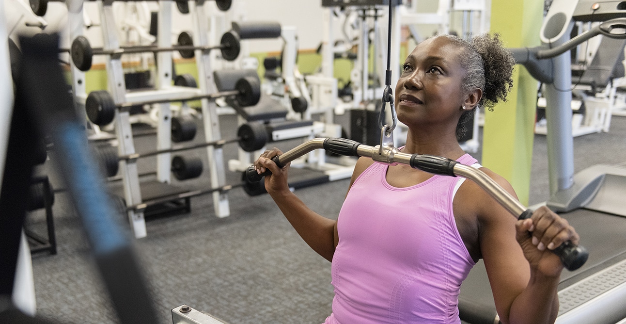 A woman uses weight lifting equipment at a wellness center.