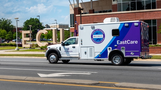 An ECU Health EastCare ambulance drives down a road.