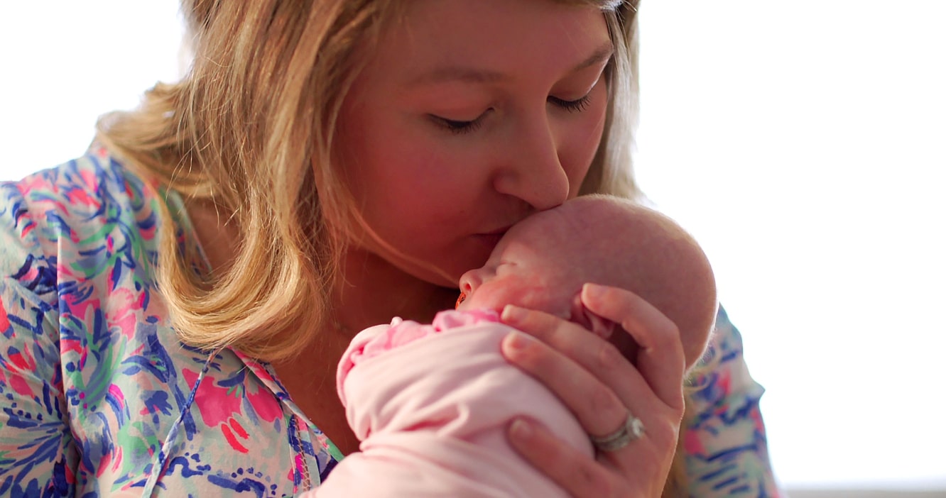 A mother kisses her newborn child's forehead.