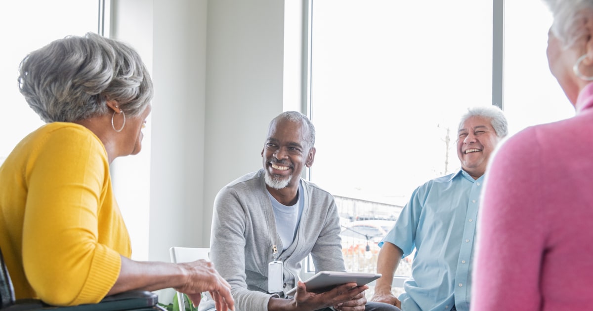 An older group of community members talk with each other during a support group meeting.