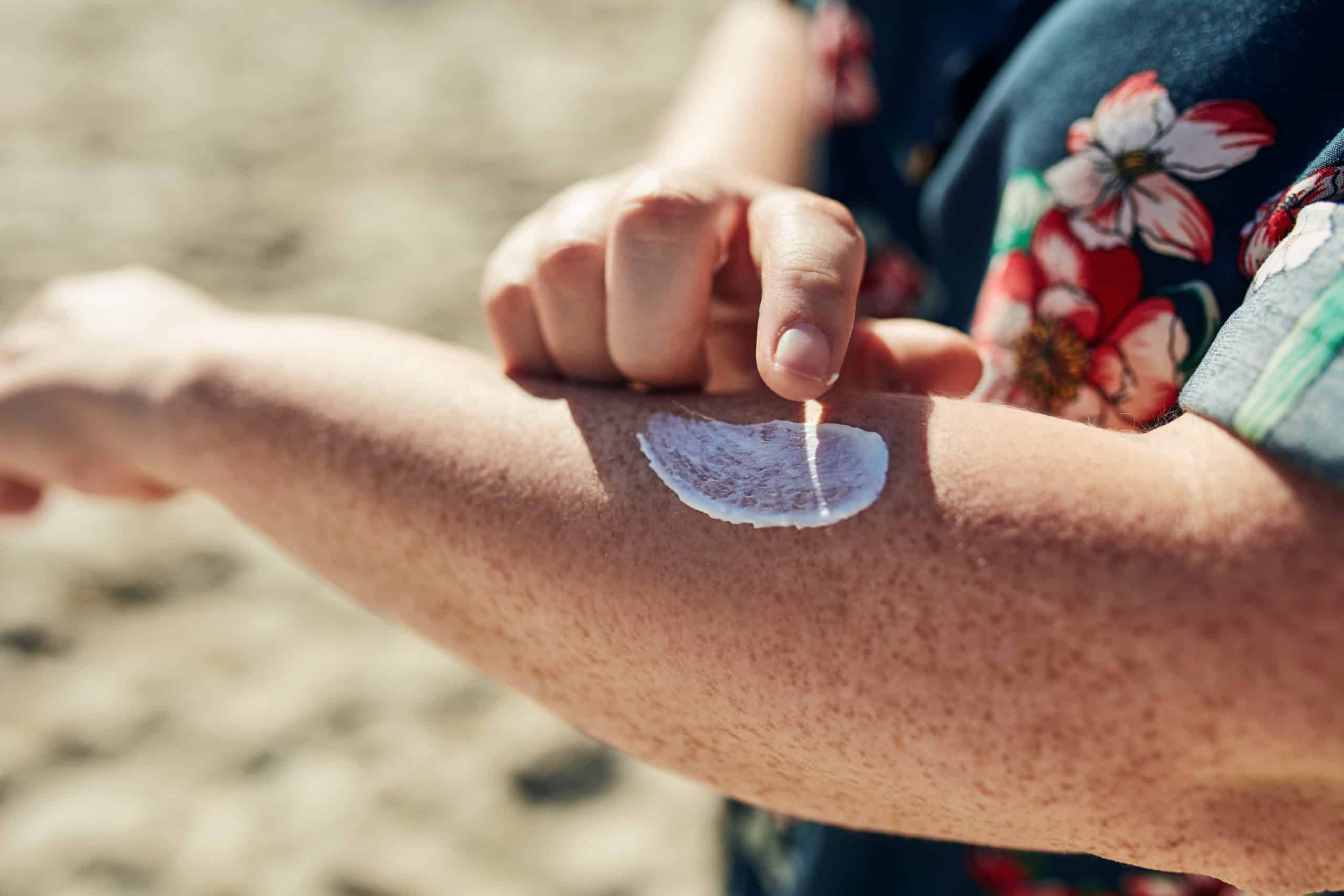 A person applies sunscreen to their skin