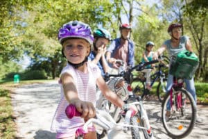 Family enjoying and riding bicycle on dirt track in park.