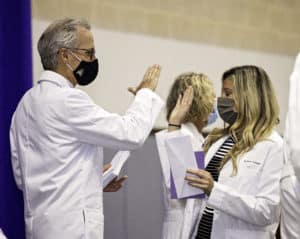 Dr. Michael Waldrum high-fives an incoming Brody School of Medicine student during the 2021 White Coat Ceremony