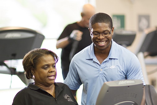 A trainer works with a woman while she works out.