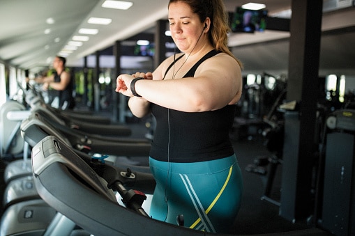 A woman checks her smart watch while exercising.