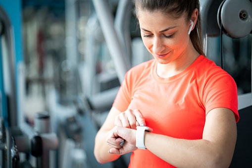 Beautiful fitness woman in gym with smart watch A woman checks her smart watch during a workout.