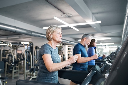 A group exercise of people run and walk on treadmills.