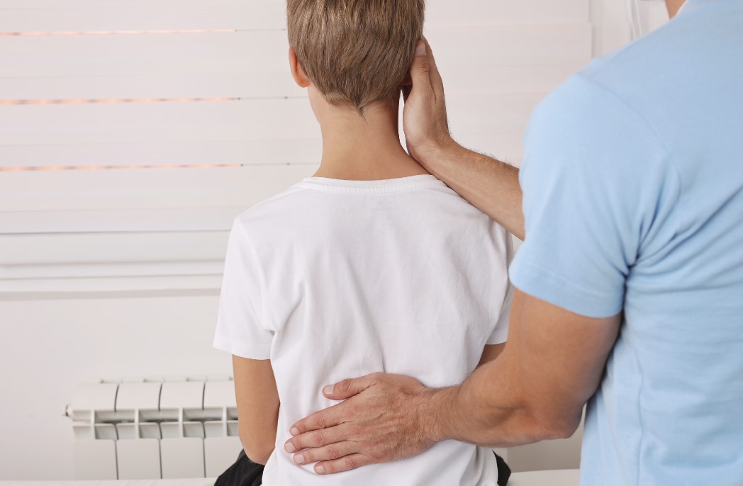 A pediatric patient is checked for scoliosis by a health care provider.
