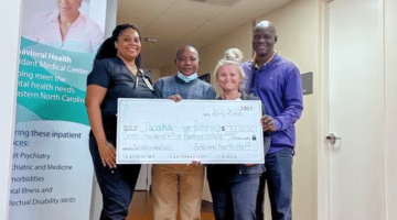 Team members pose around a check that will benefit children of Taloha in Tanzania.