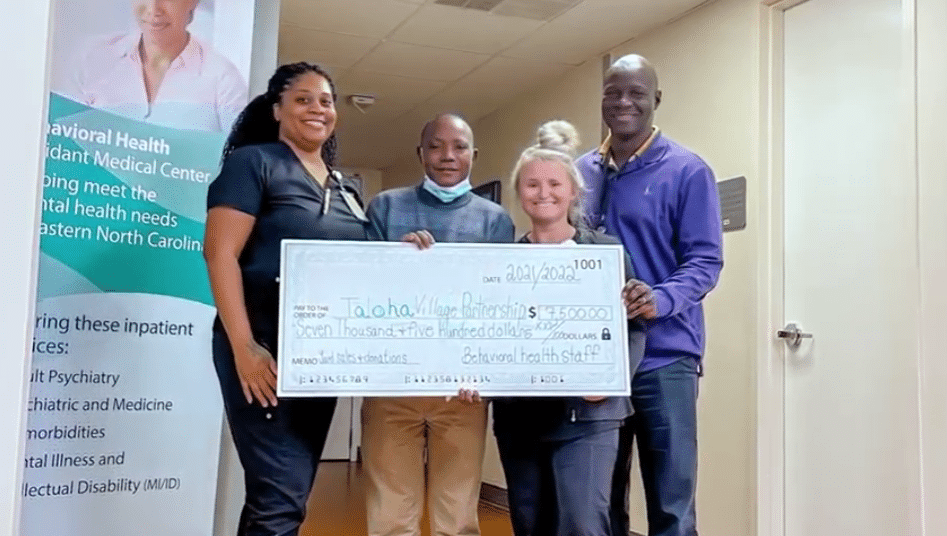 Team members pose around a check that will benefit children of Taloha in Tanzania.