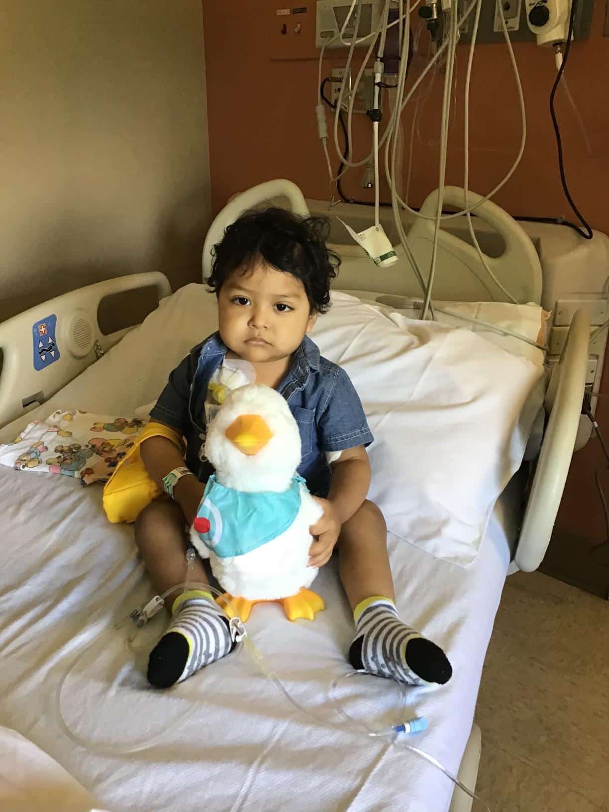 Pediatric patient Miguel Morales sits in a hospital bed with a stuffed animal.