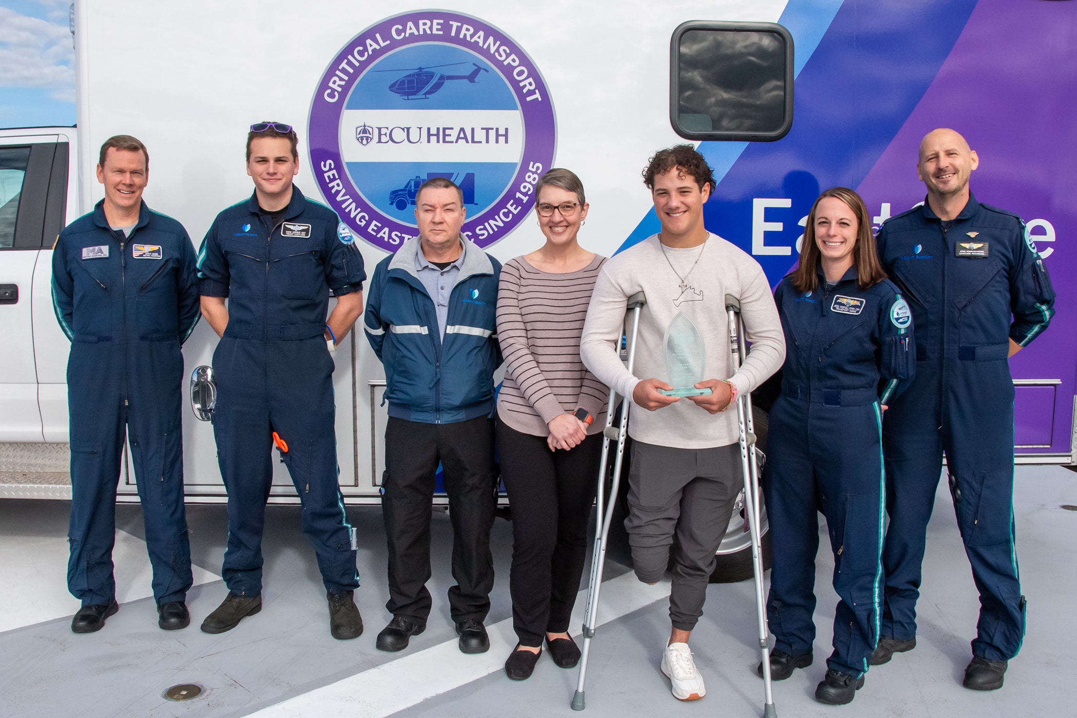 Parker Byrd and his care team pose for a photo outside of an ECU Health EastCare ambulance to celebrate the Patient Transport of the Year Award.