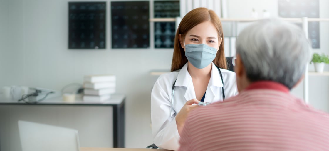 An infectious disease provider talks with a patient while wearing a mask.