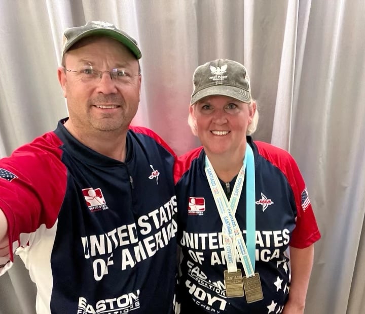 Wendy Gardner poses for a photo with her husband while wearing medals earned in Santiago, Chile.