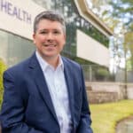 Jay Briley, ECU Health Community Hospitals president, stands outside of the ECU Health administration building and smiles into a camera.