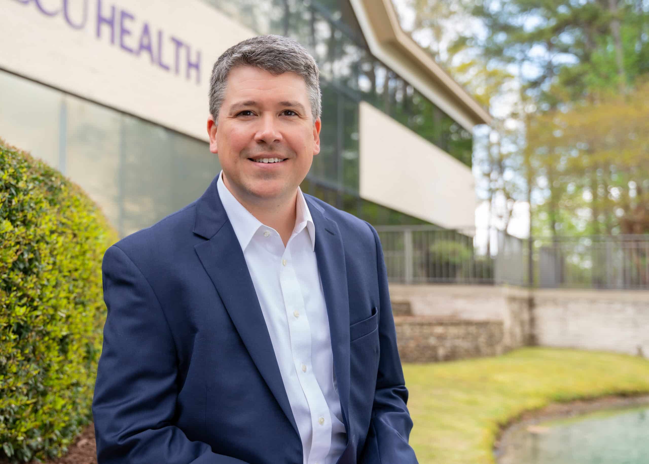Jay Briley, ECU Health Community Hospitals president, stands outside of the ECU Health administration building and smiles into a camera.