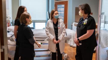 ECU Health Chief Nursing Executive Trish Baise talks with a team of nurses in a patient's room.