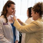 Dr. Julie Kennedy Oehlert, chief experience officer at ECU Health, places a pin on a Brody School of Medicine student during the ECU Health and Brody Legacy Teachers event.