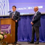 ECU Health Chief Operating Officer and President of ECU Health Medical Center Brian Floyd stands on stage during the ECU Health and Brody School of Medicine Legacy Teachers event.