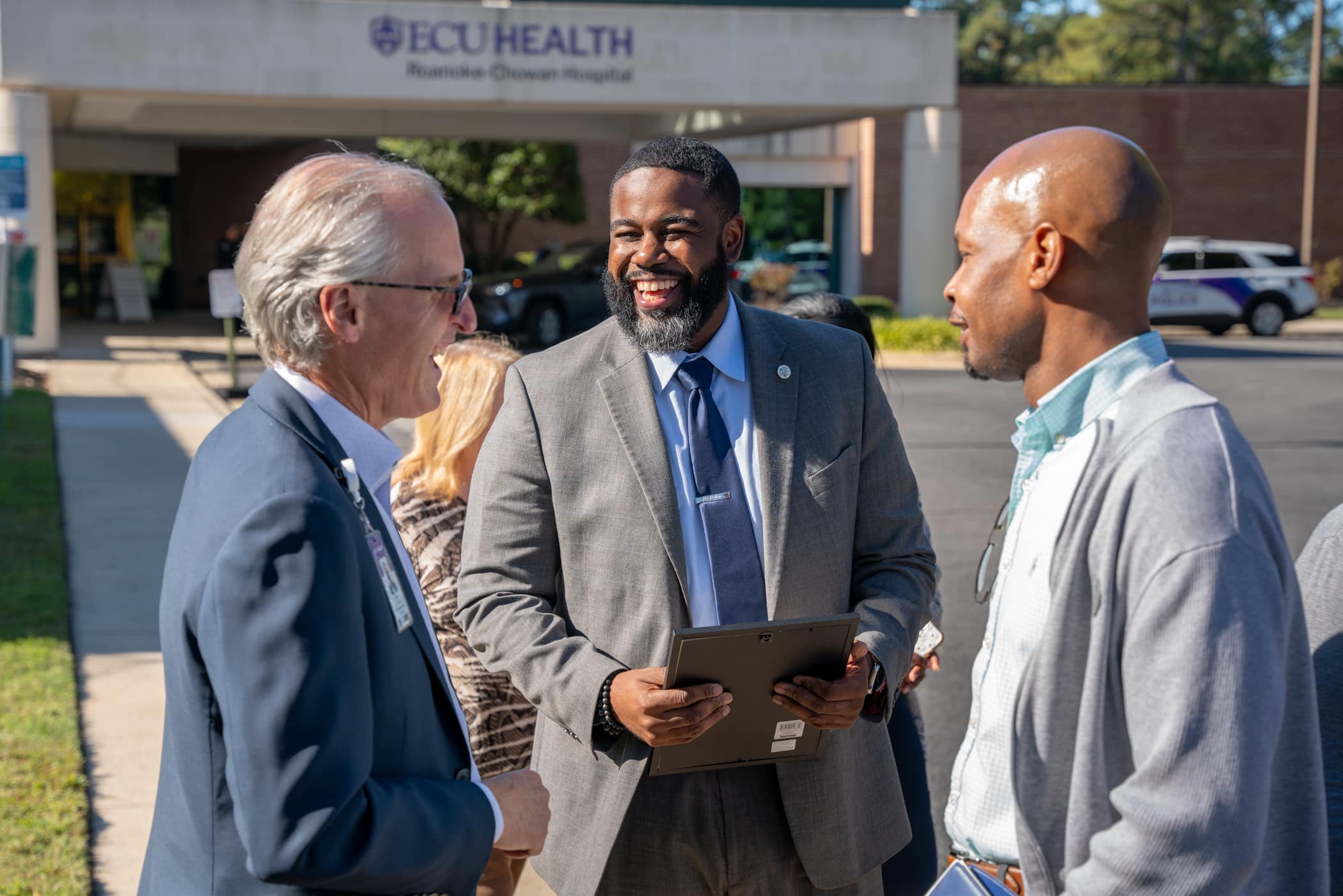 ECU Health CEO Dr. Michael Waldrum speaks to two community leaders at ECU Health Roanoke-Chowan Hospital during the 75th anniversary for the hospital.