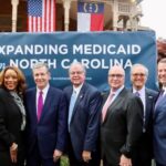 Dr. Michael Waldrum joins Gov. Roy Cooper and other elected officials after the Medicaid expansion bill signing in Raleigh.