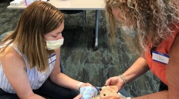 Two ECU Health volunteers work on a memory bear for a family to remember their loved one.