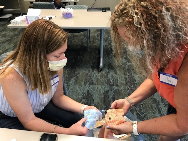 Two ECU Health volunteers work on a memory bear for a family to remember their loved one.