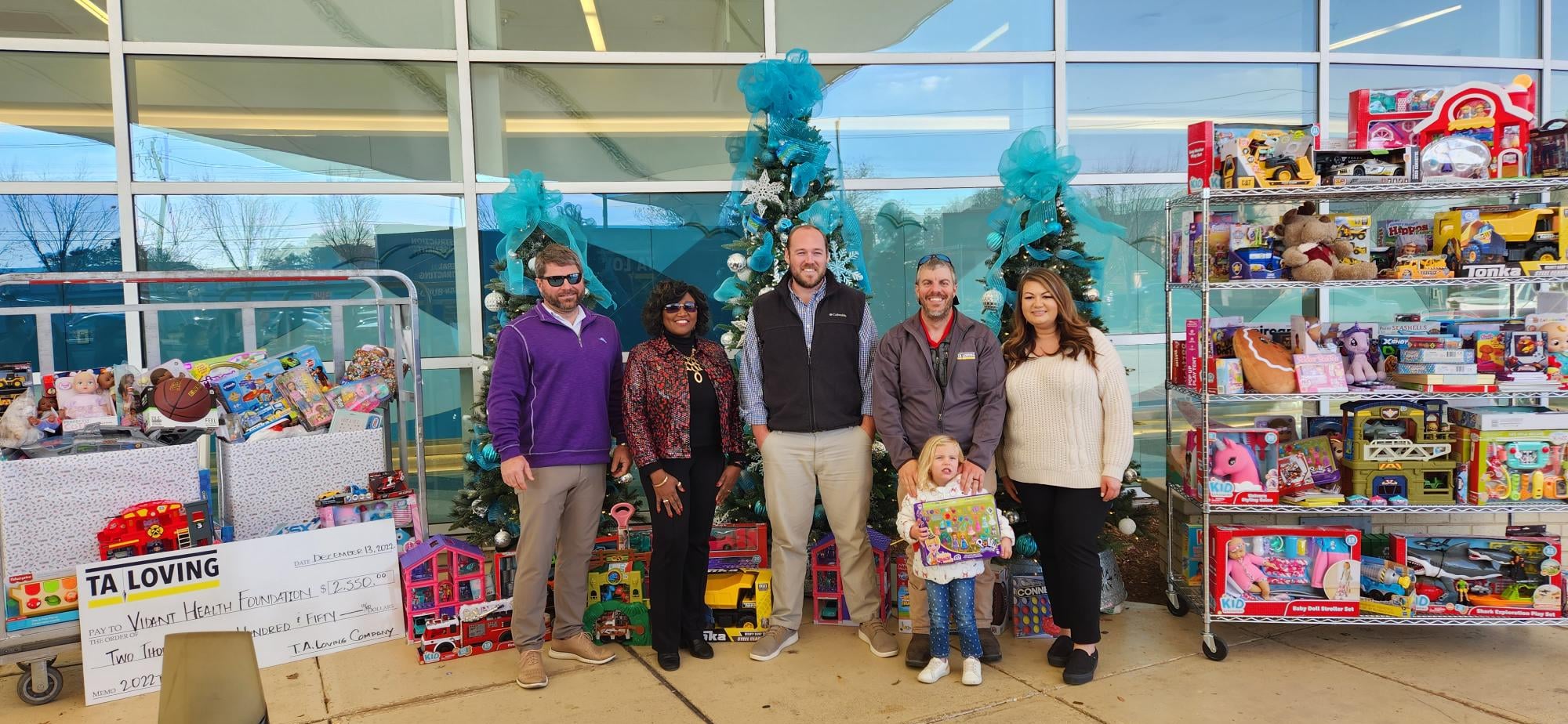 A team of TA Loving representatives stand outside of Maynard Children's Hospital at ECU Health Medical Center with a holiday donation for the children at the hospital.