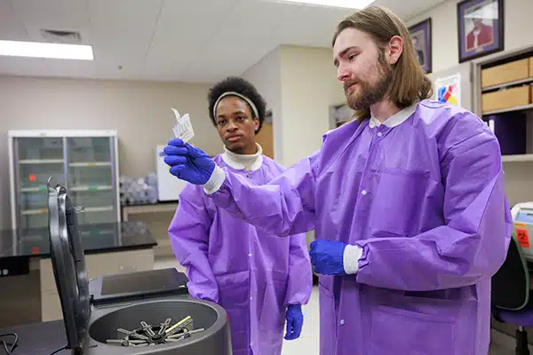 ECU clinical laboratory science students Michael Foster, right, and Bryce Glover examine a gel assay testing cartridge at the College of Allied Health Sciences.