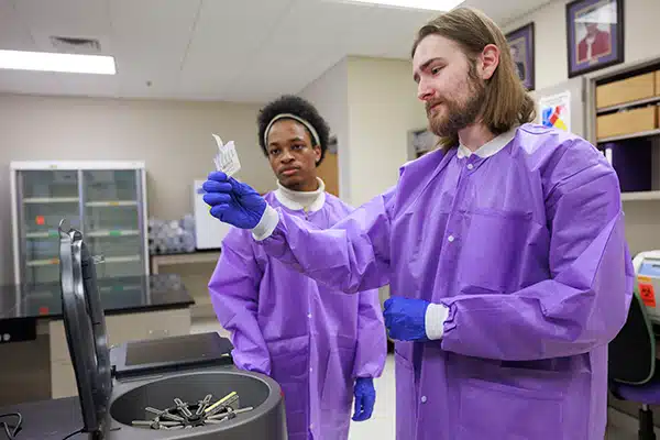 01-22-24-Clinical-Sciences-9936_600 ECU clinical laboratory science students Michael Foster, right, and Bryce Glover examine a gel assay testing cartridge at the College of Allied Health Sciences.