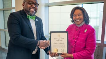 Chad Tucker, director of the Volunteer Services Department at the Medical Center, shakes hands with Jennifer Congleton, administrator of pastoral care and volunteer services, while they hold the North Carolina Governor’s Award for Volunteer Service: Paid Volunteer Director.