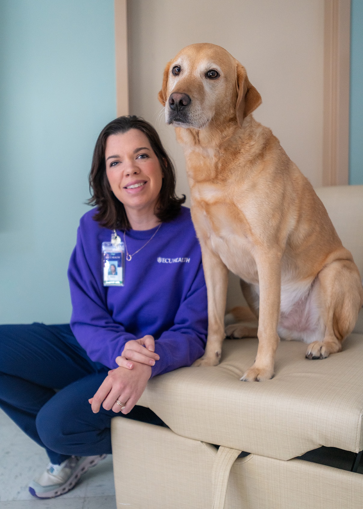 Kasey Shue, a recreational therapist at ECU Health Medical Center, sits with Clive, an Animal Assisted Therapy dog, on the rehab unit at the Medical Center. Shue is Clive's handler.