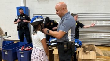 A local law enforcement officer helps a student get fitted for a bike helmet during a recent community event.