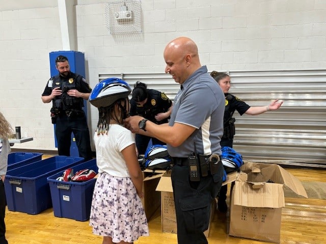 A local law enforcement officer helps a student get fitted for a bike helmet during a recent community event.