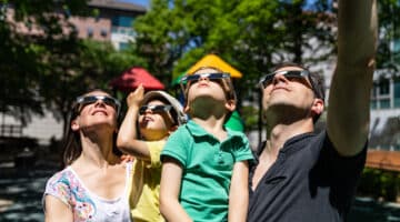 A family looks at a solar eclipse in a public park.