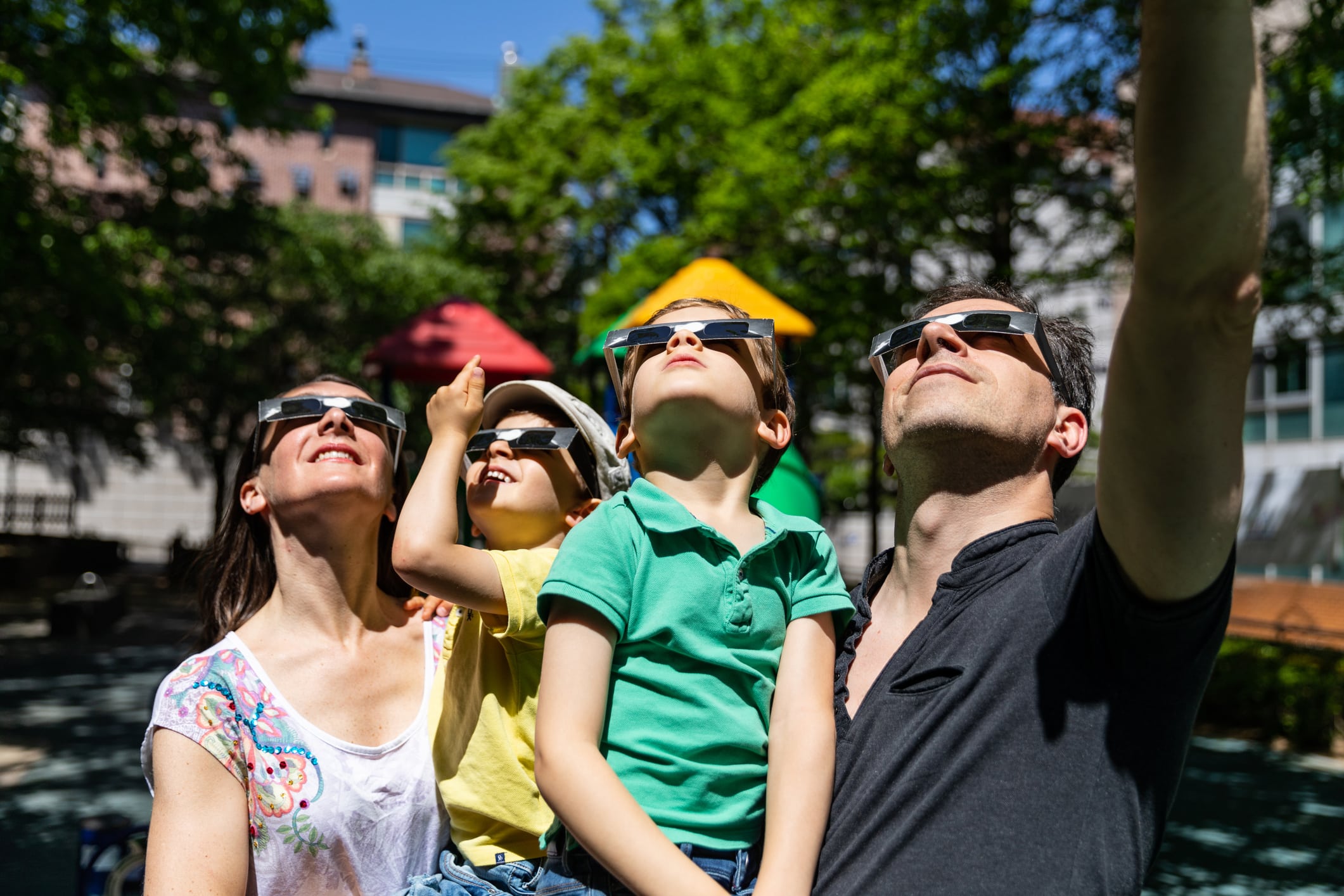 All the family look at solar eclipse in the city street in a public park A family looks at a solar eclipse in a public park.