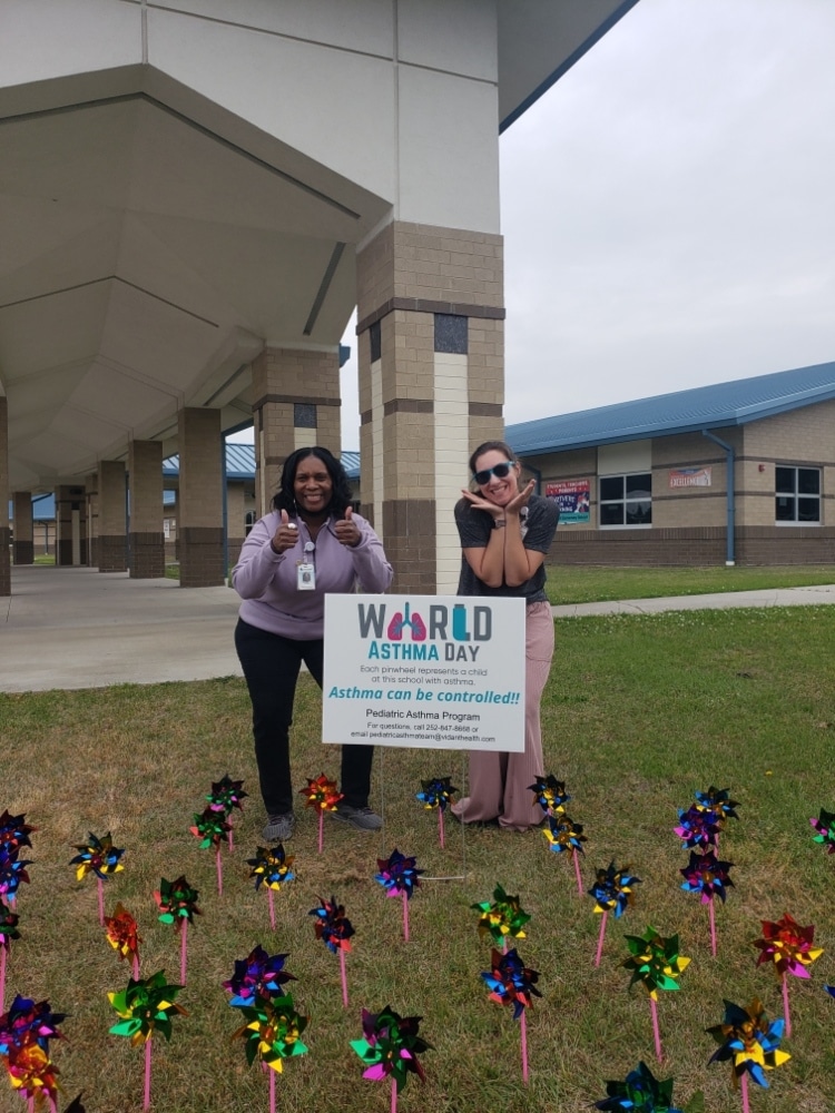 Two ECU Health Pediatric Asthma care team members pose for a photo in front of a World Asthma Day sign.