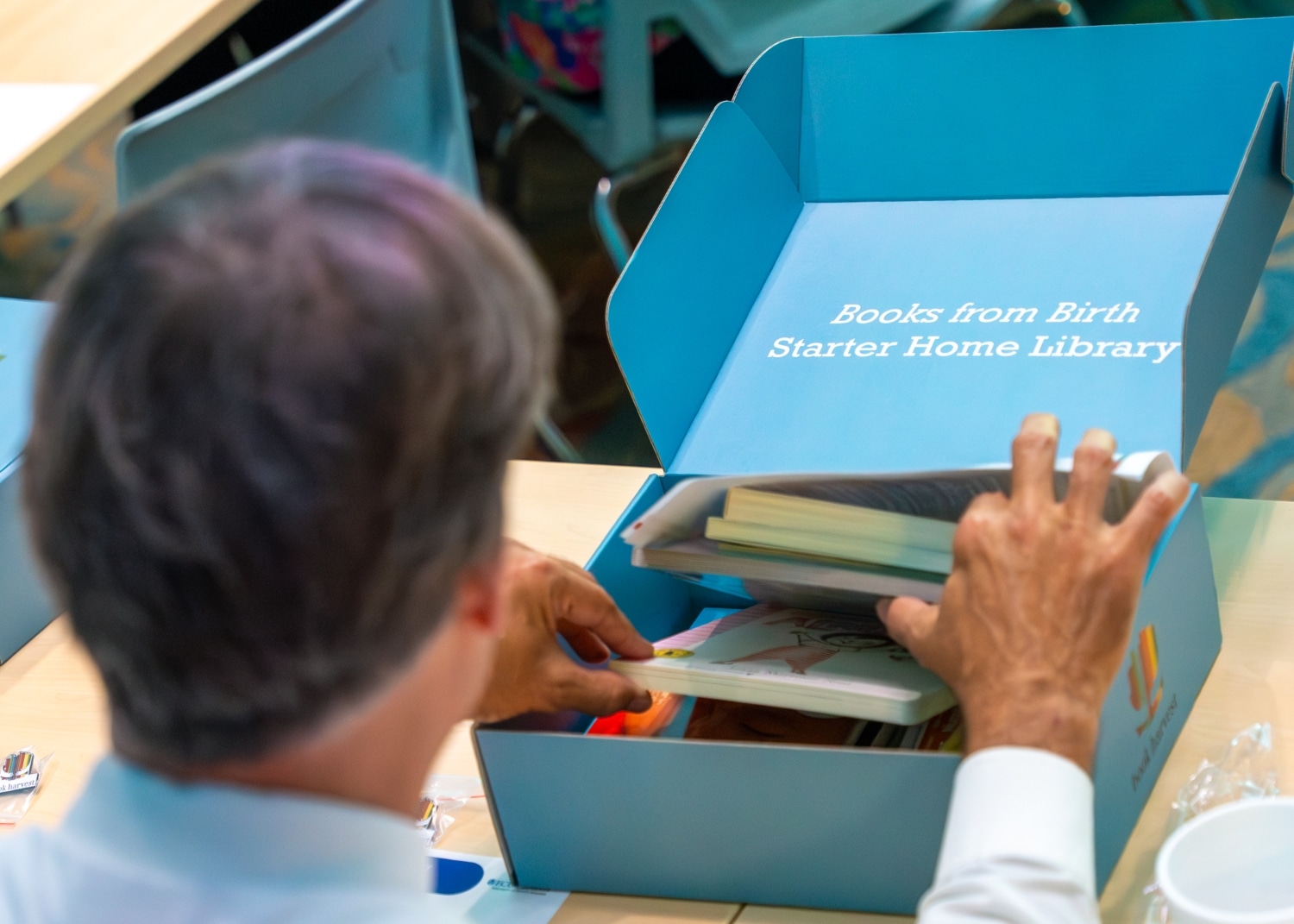 MCH-Book Harvest-8262-Enhanced-NR (1) A volunteer fills a home library box for families of newborns during a Book Harvest event.