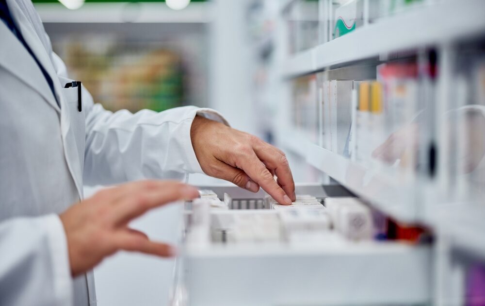 A pharmacist looks through medications in a drawer.