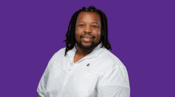 ECU Health NICU nurse David Roberts poses for a photo in front of a purple backdrop.