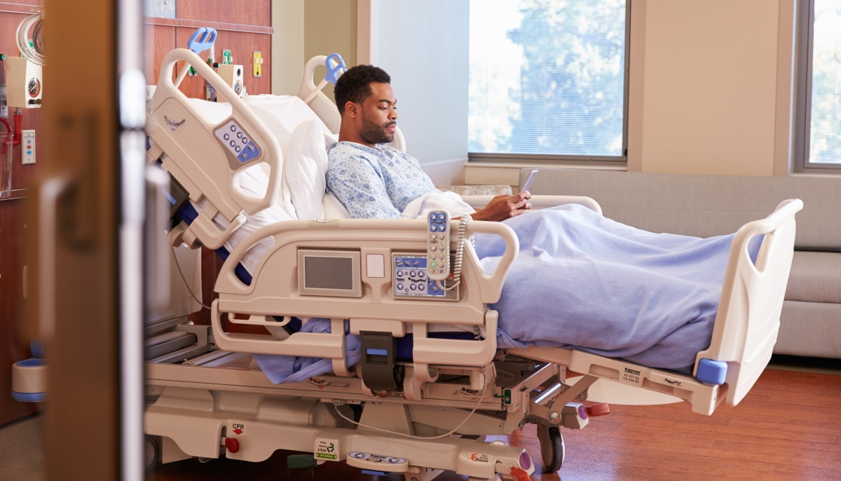 MyChart Bedside A patient sits in a hospital bed while using their phone.