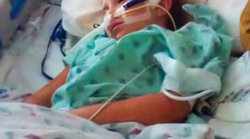 Kayla Jordan lays in a bed at Maynard Children's Hospital.