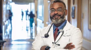 Dr. Anthony Smith poses for a photo with his arms crossed and smiling in a hallway at ECU Health Medical Center.