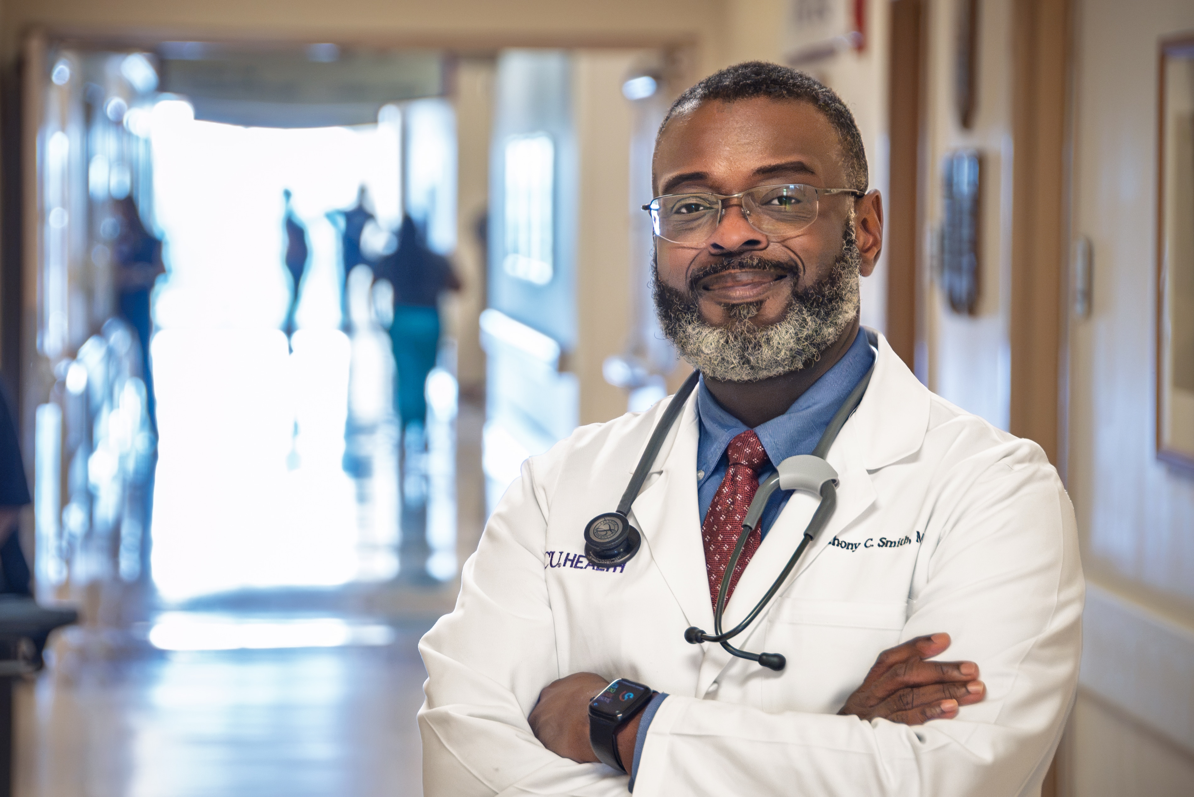 Anthony Smith-5477 Dr. Anthony Smith poses for a photo with his arms crossed and smiling in a hallway at ECU Health Medical Center.